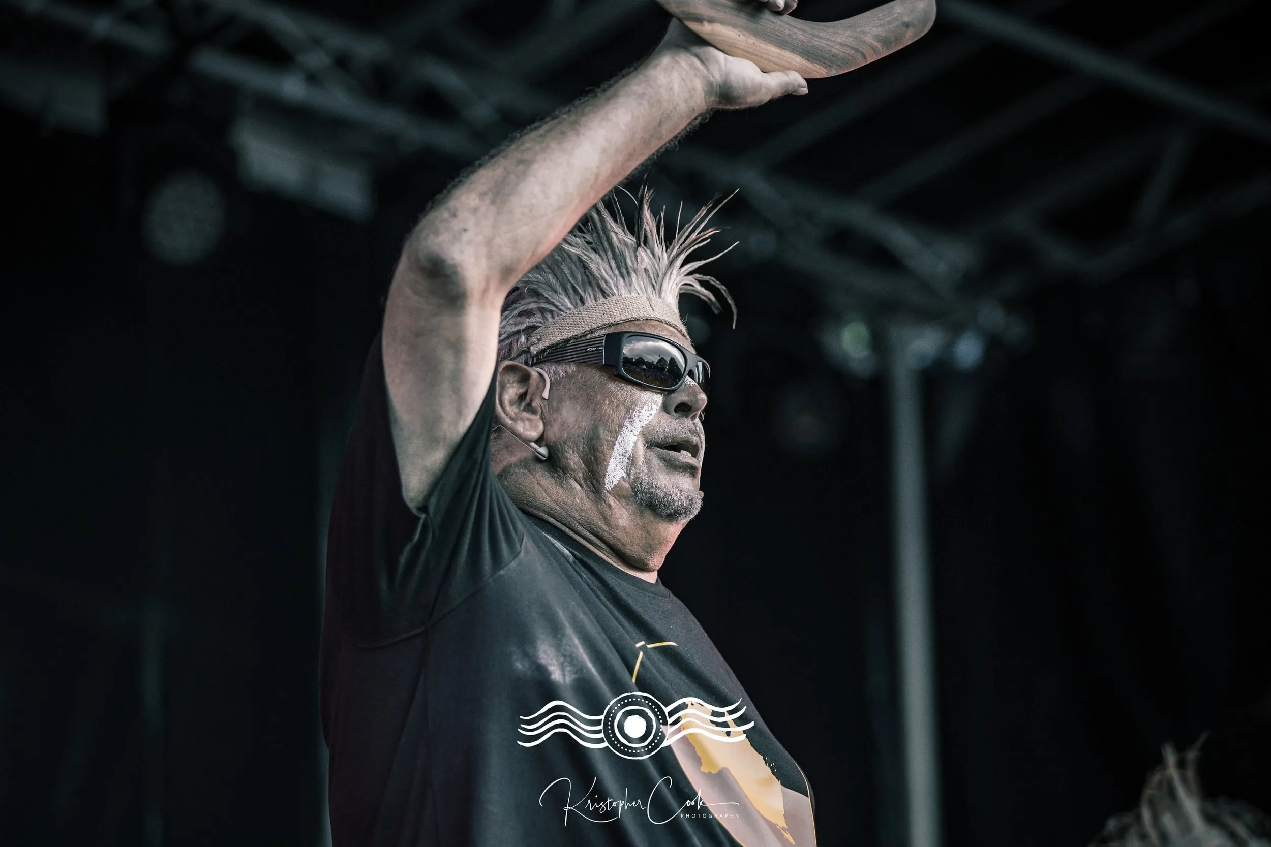 Elder with arms raised on stage at Groove on the Grass, Grafton, 2023, photographed by Kris Cook