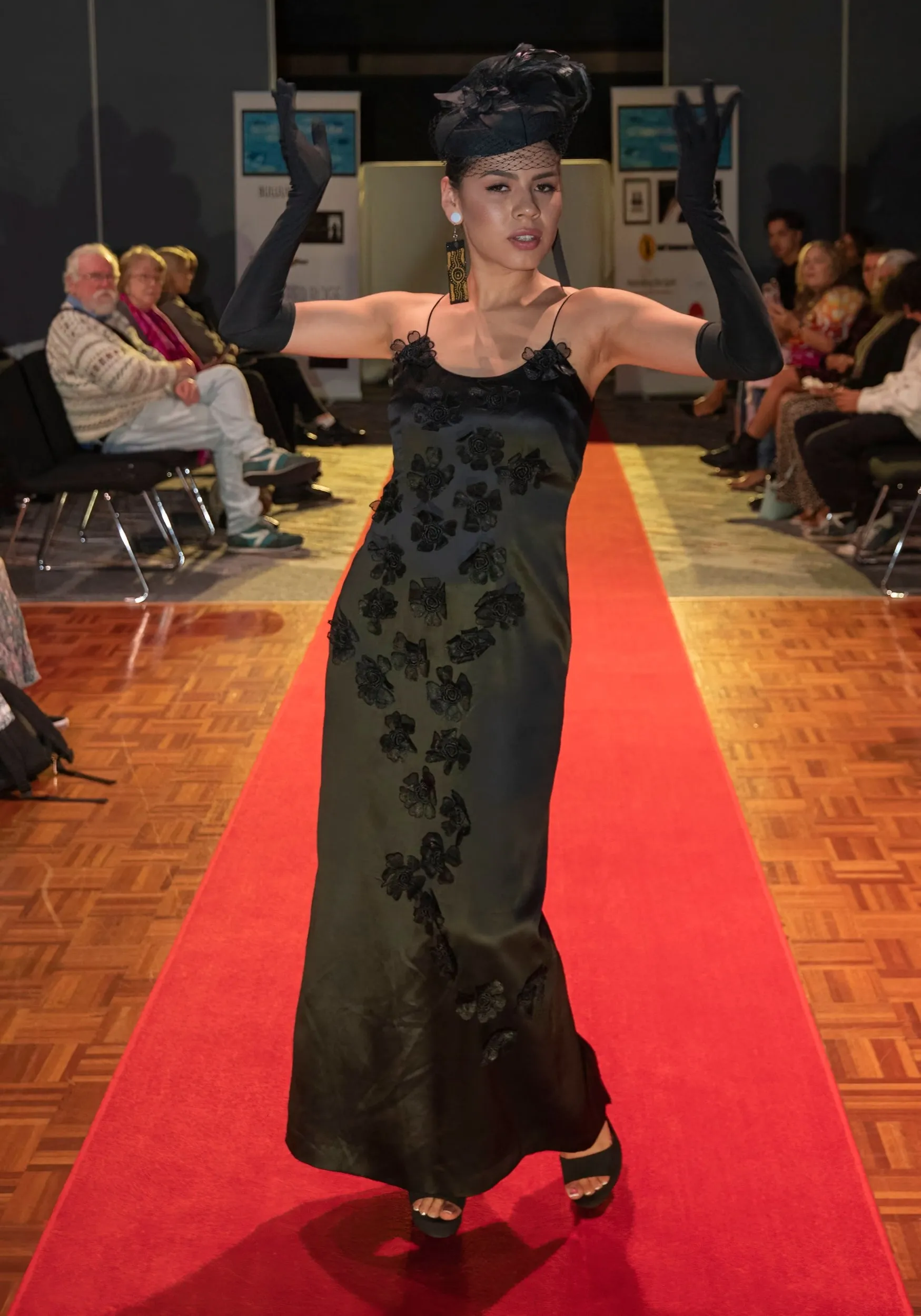 Model in a black gown with arms out at the Guyamgan Bahna Fashion Show, Gold Coast, 2022, photographed by Kris Cook